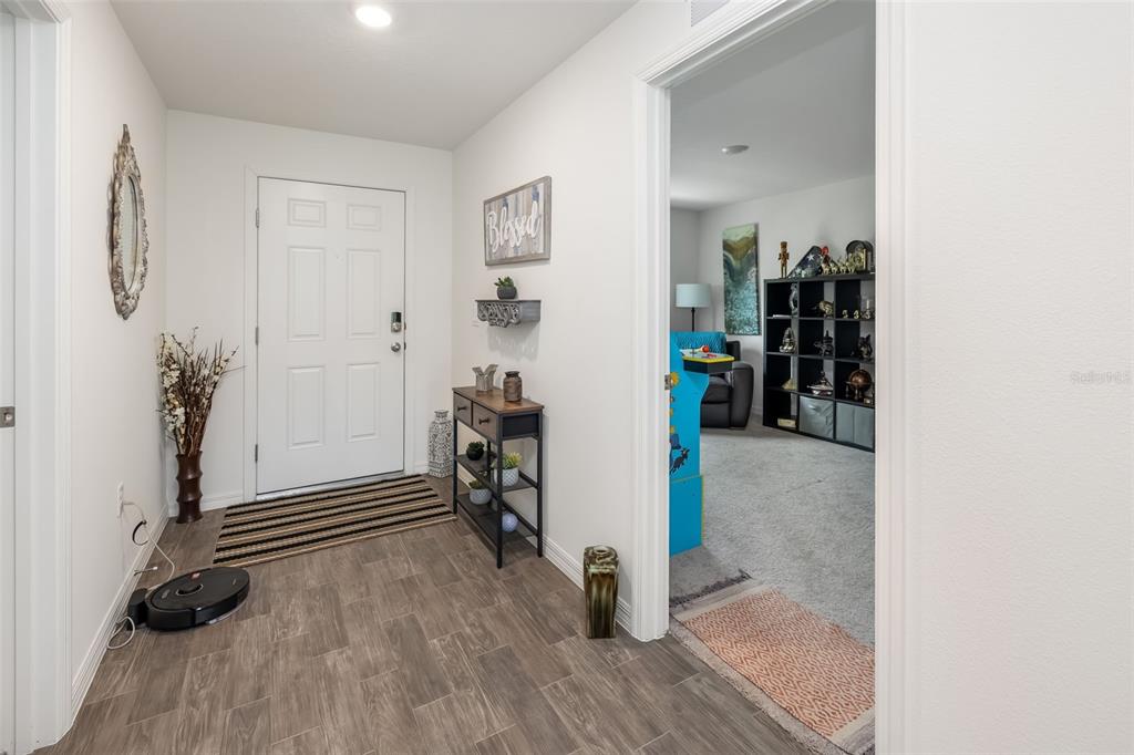 An entryway with wood-look tile flooring leads to a carpeted room through a doorway — 49 LLAMA TRAIL, PALM COAST, FL