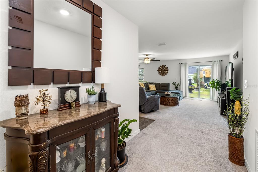 A foyer with a marble-topped cabinet and mirror leads into a carpeted living room — 49 LLAMA TRAIL, PALM COAST, FL