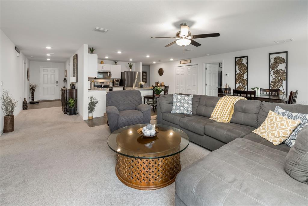 A living room with a gray sectional sofa, round coffee table, and open-concept kitchen — 49 LLAMA TRAIL, PALM COAST, FL