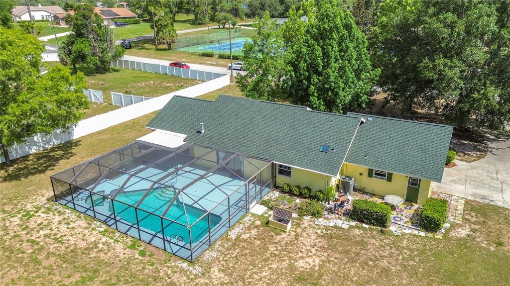 An aerial view of a yellow house with a green roof and a screened-in pool — 2016 W MELLINE LANE, LECANTO, FL