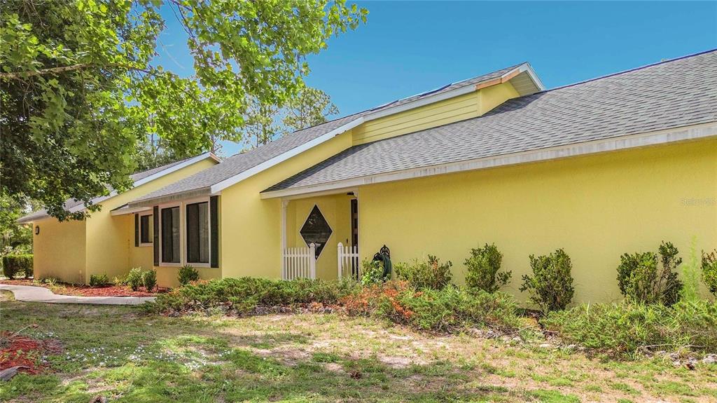 A yellow single-story house with a gray shingled roof and a small front porch — 2016 W MELLINE LANE, LECANTO, FL