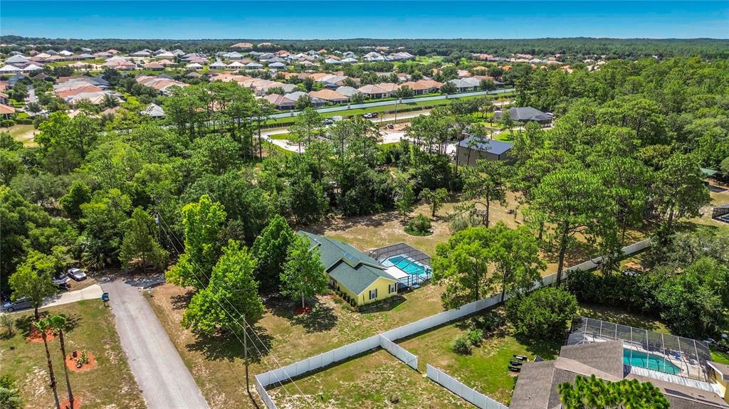 An aerial view shows a yellow house with a pool and a white fence — 2016 W MELLINE LANE, LECANTO, FL