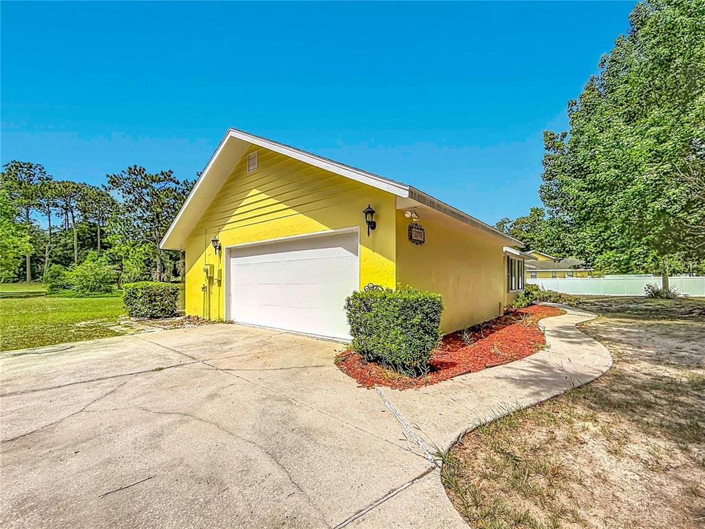 A yellow detached garage with a white door and a concrete driveway — 2016 W MELLINE LANE, LECANTO, FL