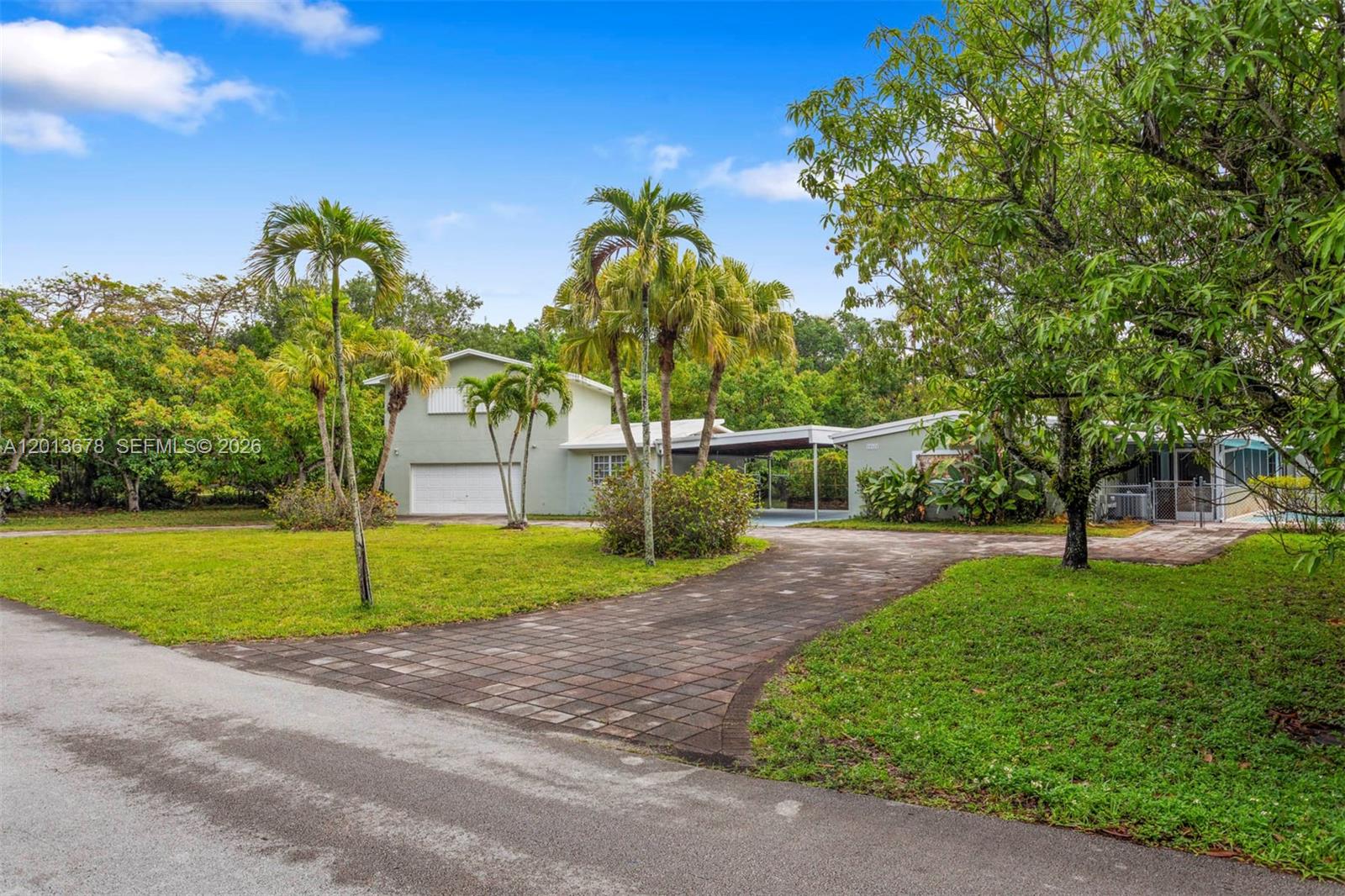A two-story house with a paved driveway, carport, and palm trees in the front yard — 10851 SW 68th Ave, Pinecrest FL 33156, PINECREST, FL