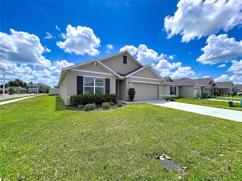 A single-story suburban house with a tan exterior, a two-car garage, and a green lawn — 7804 DAVIE RAY DRIVE, ZEPHYRHILLS, FL