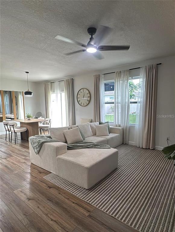 A living room features a sectional sofa, a dining area, and a striped area rug — 9016 PYRUS STREET, KISSIMMEE, FL