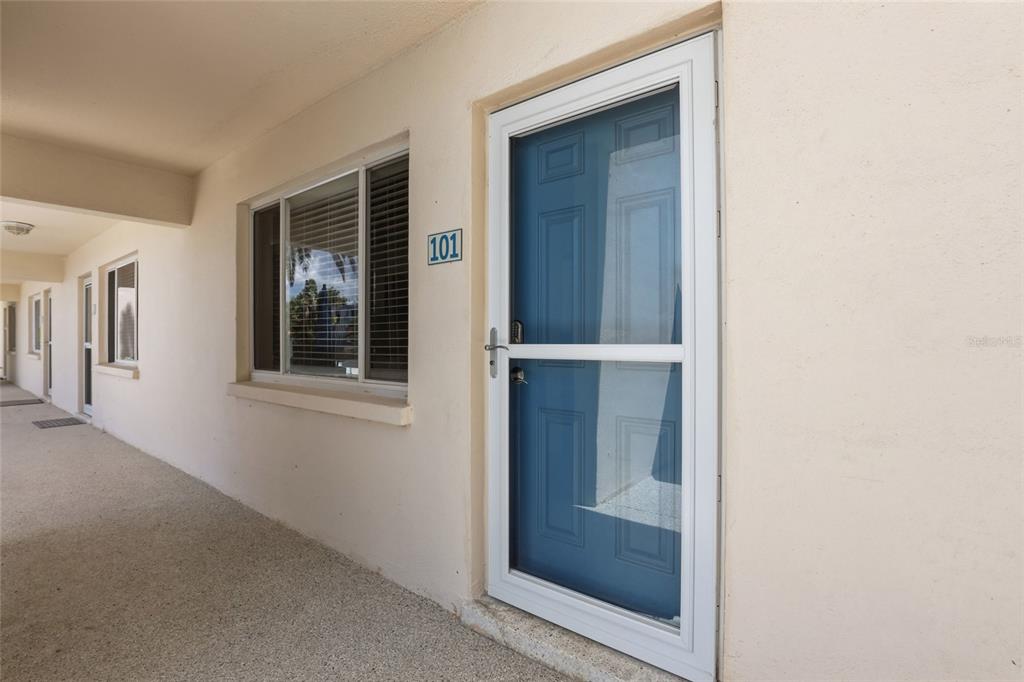 A blue front door with a white storm door and a window at unit 101 — 5950 MIDNIGHT PASS ROAD UNIT 101, SARASOTA, FL
