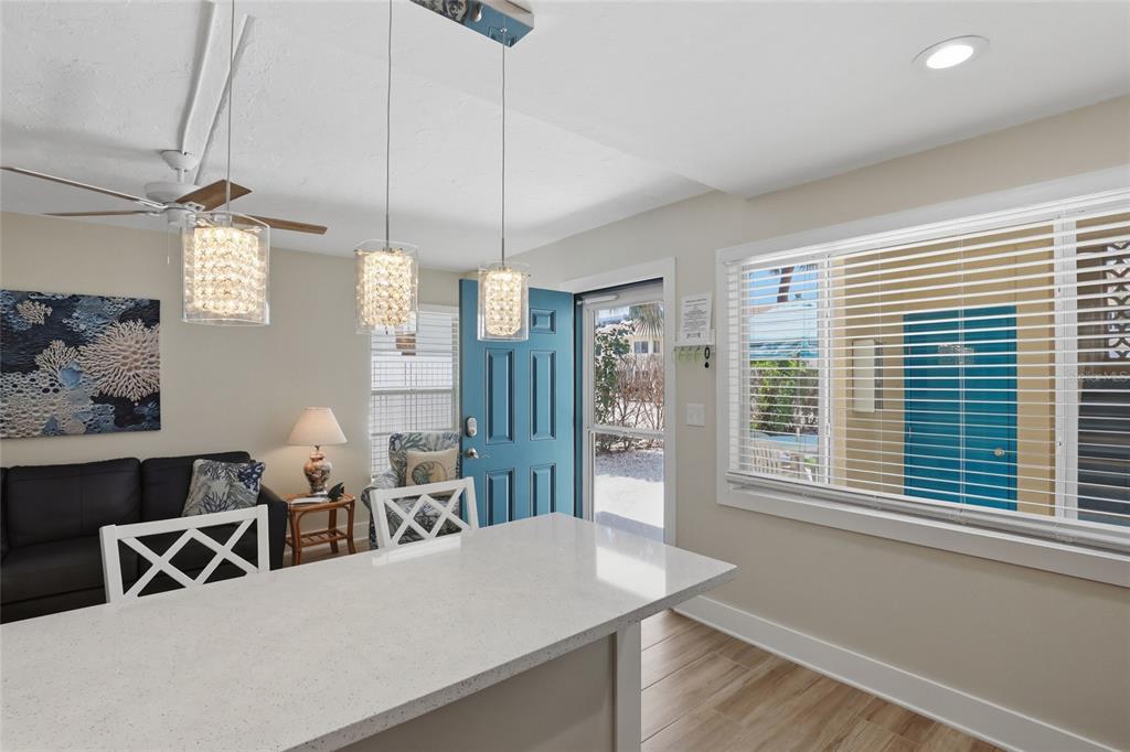 A kitchen island with white quartz countertops sits in front of a blue entry door — 5950 MIDNIGHT PASS ROAD UNIT 101, SARASOTA, FL
