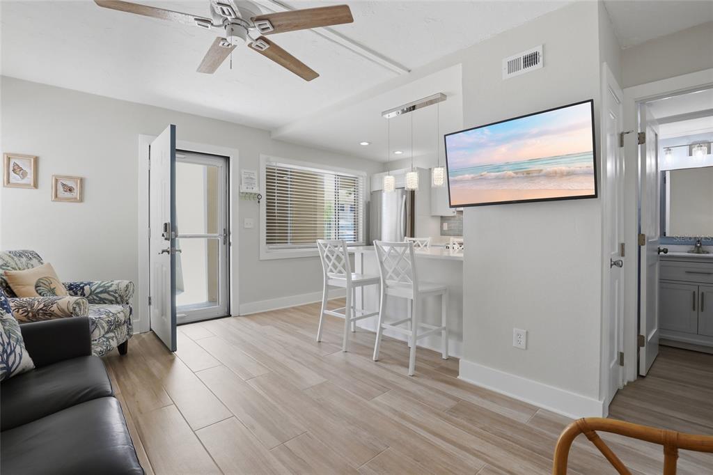 A living room and kitchen area with light wood-look tile flooring and a ceiling fan — 5950 MIDNIGHT PASS ROAD UNIT 101, SARASOTA, FL