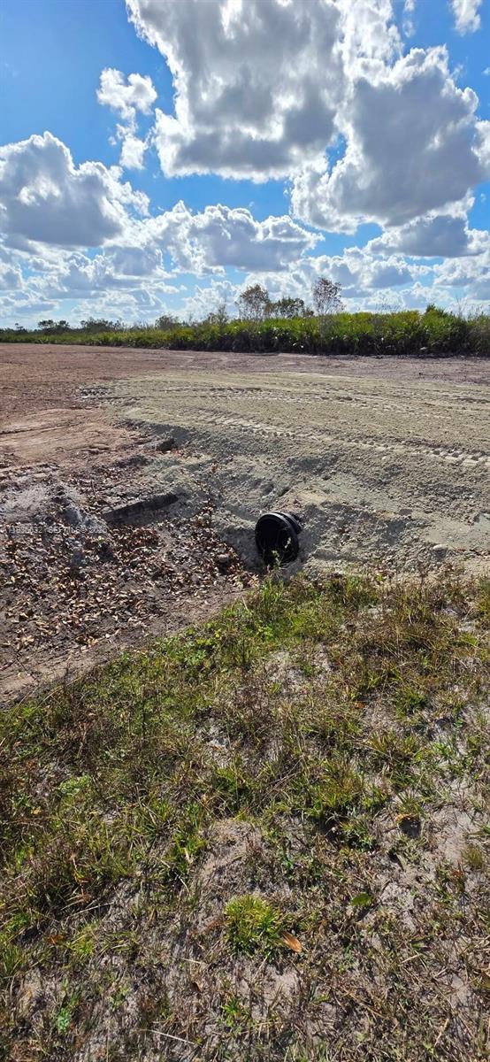 A black drainage pipe is embedded in a dirt embankment near a grassy field — 19946 NW 254 st, Okeechobee FL 34972, OKEECHOBEE, FL