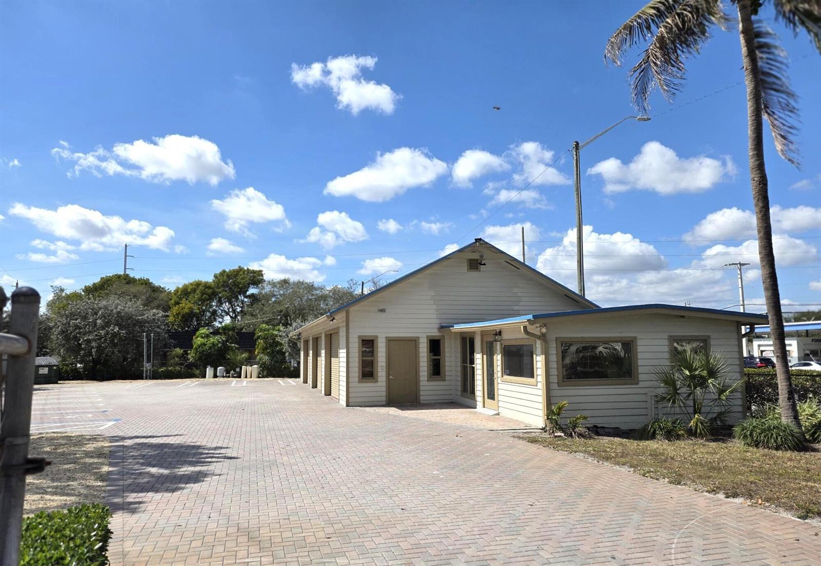 A light-colored, single-story building with a paved parking lot under a blue sky — 1710 W Atlantic Avenue, Delray Beach FL 33444, DELRAY BEACH, FL