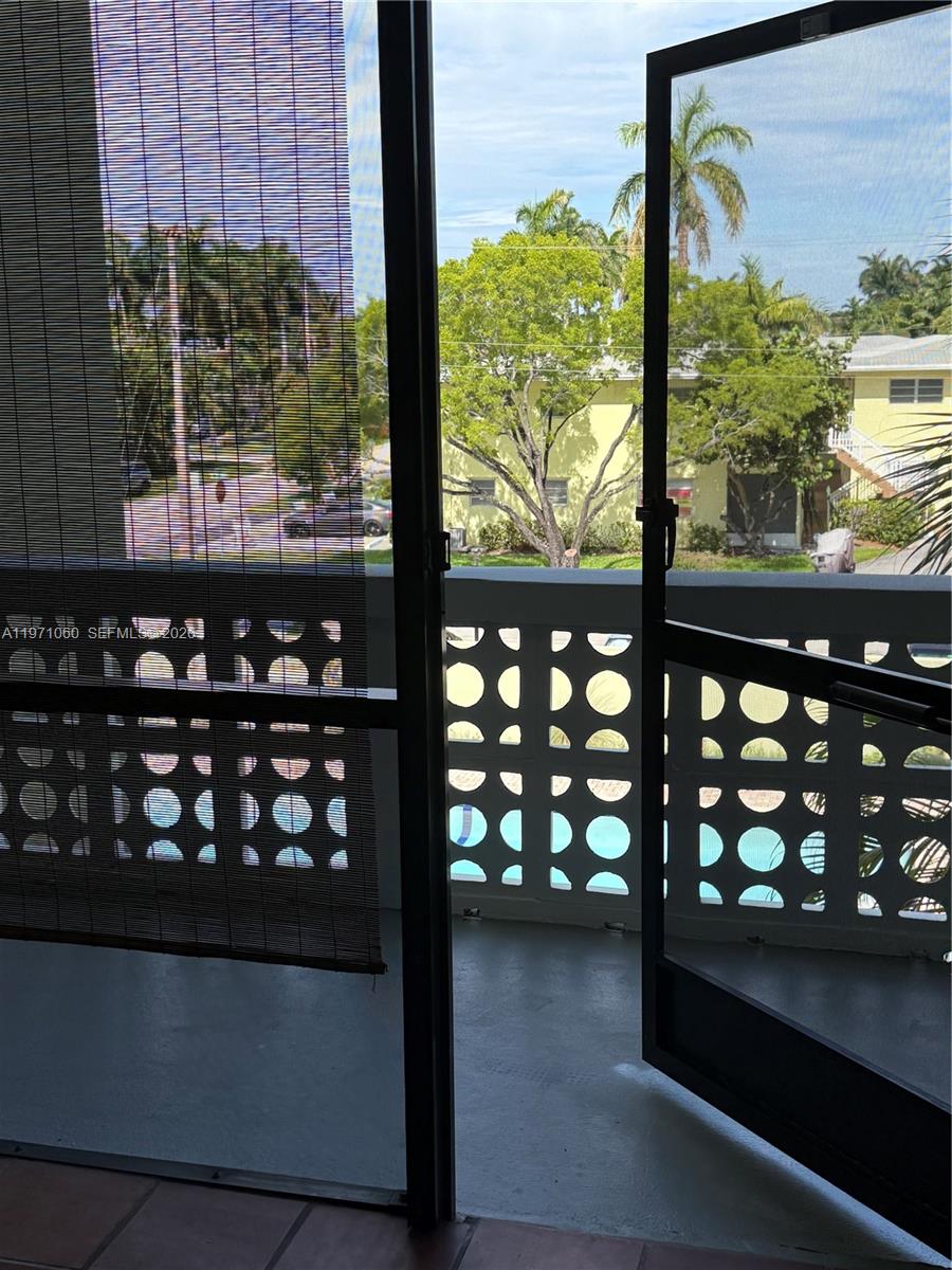 A view from a balcony through a screen door looking out toward trees and buildings — 1425 Arthur St # 315B, Hollywood FL 33020, HOLLYWOOD, FL