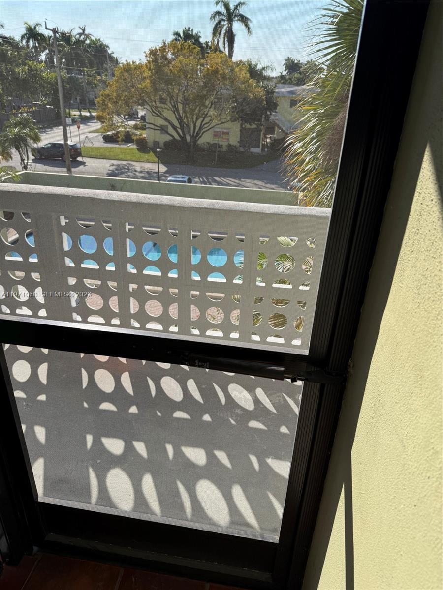 A view from a window shows a balcony with a patterned screen overlooking a pool — 1425 Arthur St # 315B, Hollywood FL 33020, HOLLYWOOD, FL