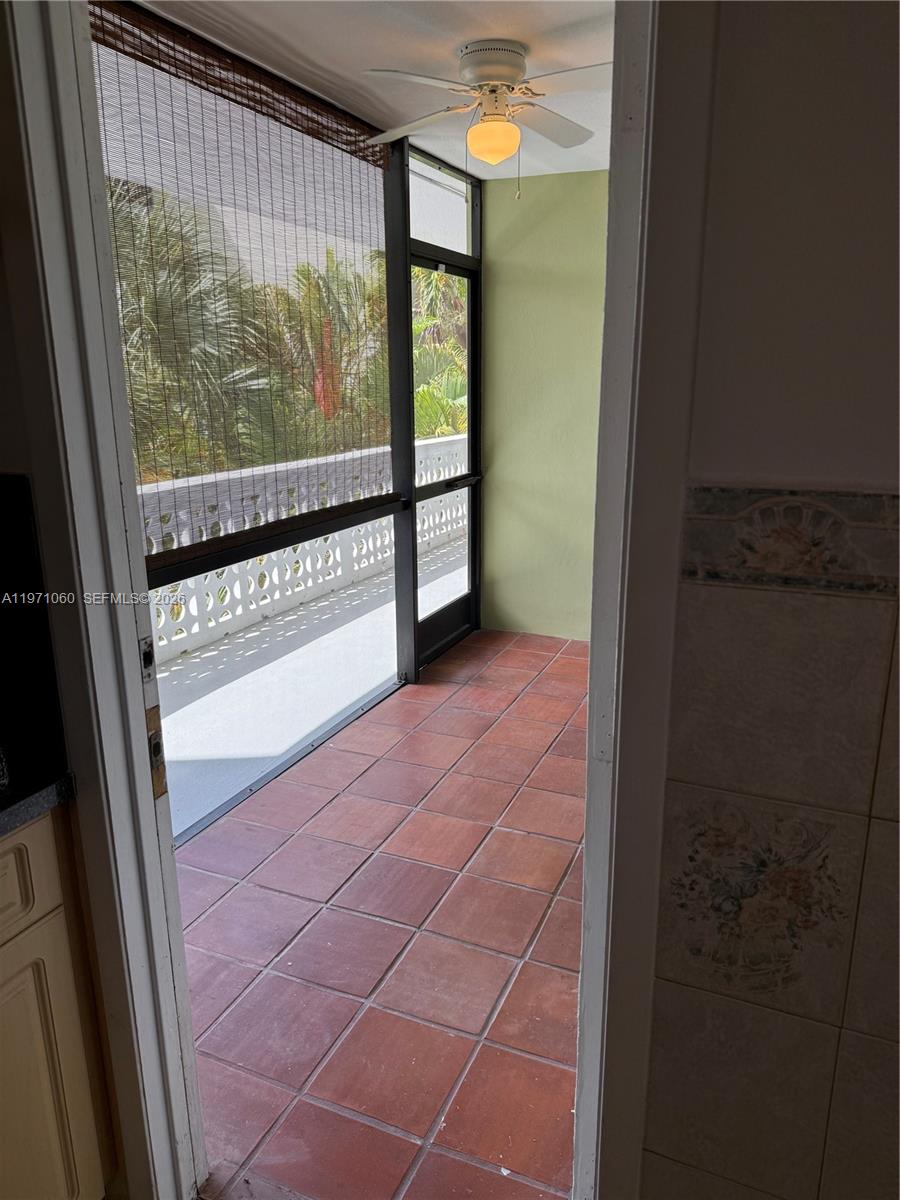 A tiled balcony with a ceiling fan and screen enclosure overlooks palm trees — 1425 Arthur St # 315B, Hollywood FL 33020, HOLLYWOOD, FL