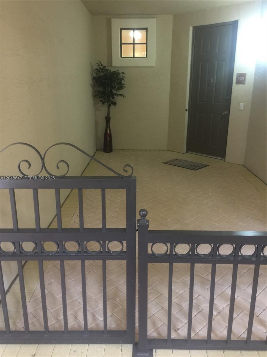 A gated entryway features a paved patio, a black front door, and tan stucco walls — 2900 NW 125th Ave # 224, Sunrise FL 33323, SUNRISE, FL