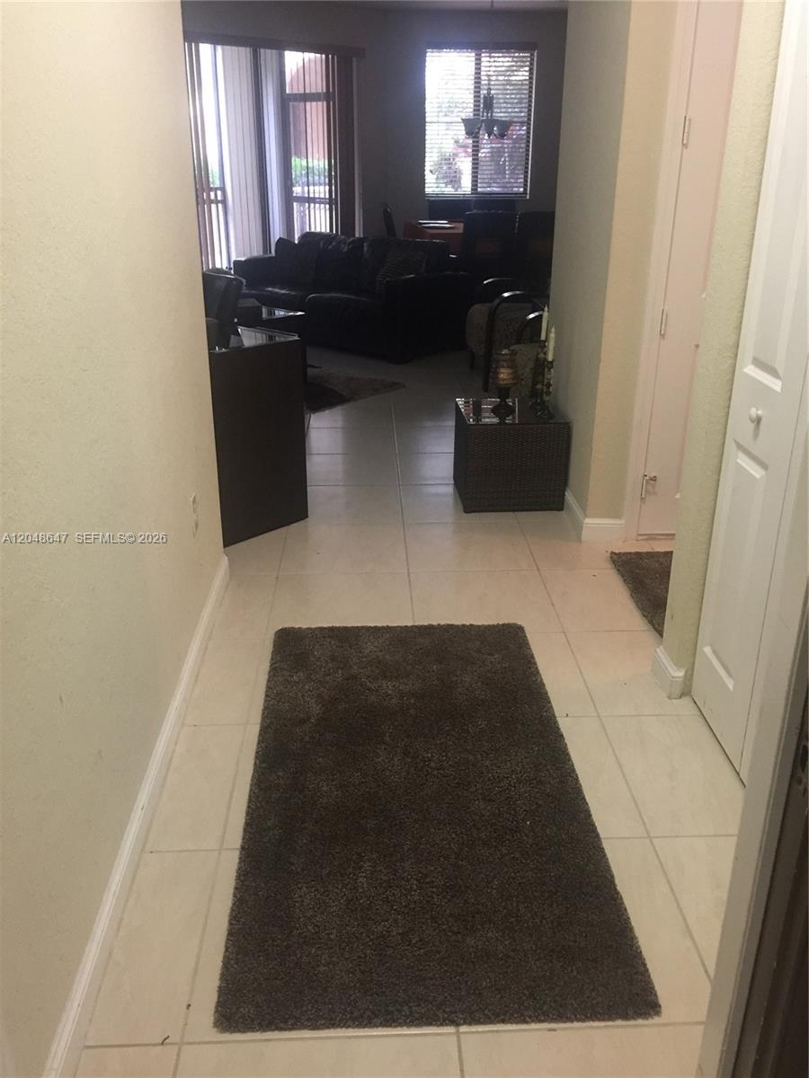 A tiled hallway leads toward an open living area with sliding glass doors and windows — 2900 NW 125th Ave # 224, Sunrise FL 33323, SUNRISE, FL