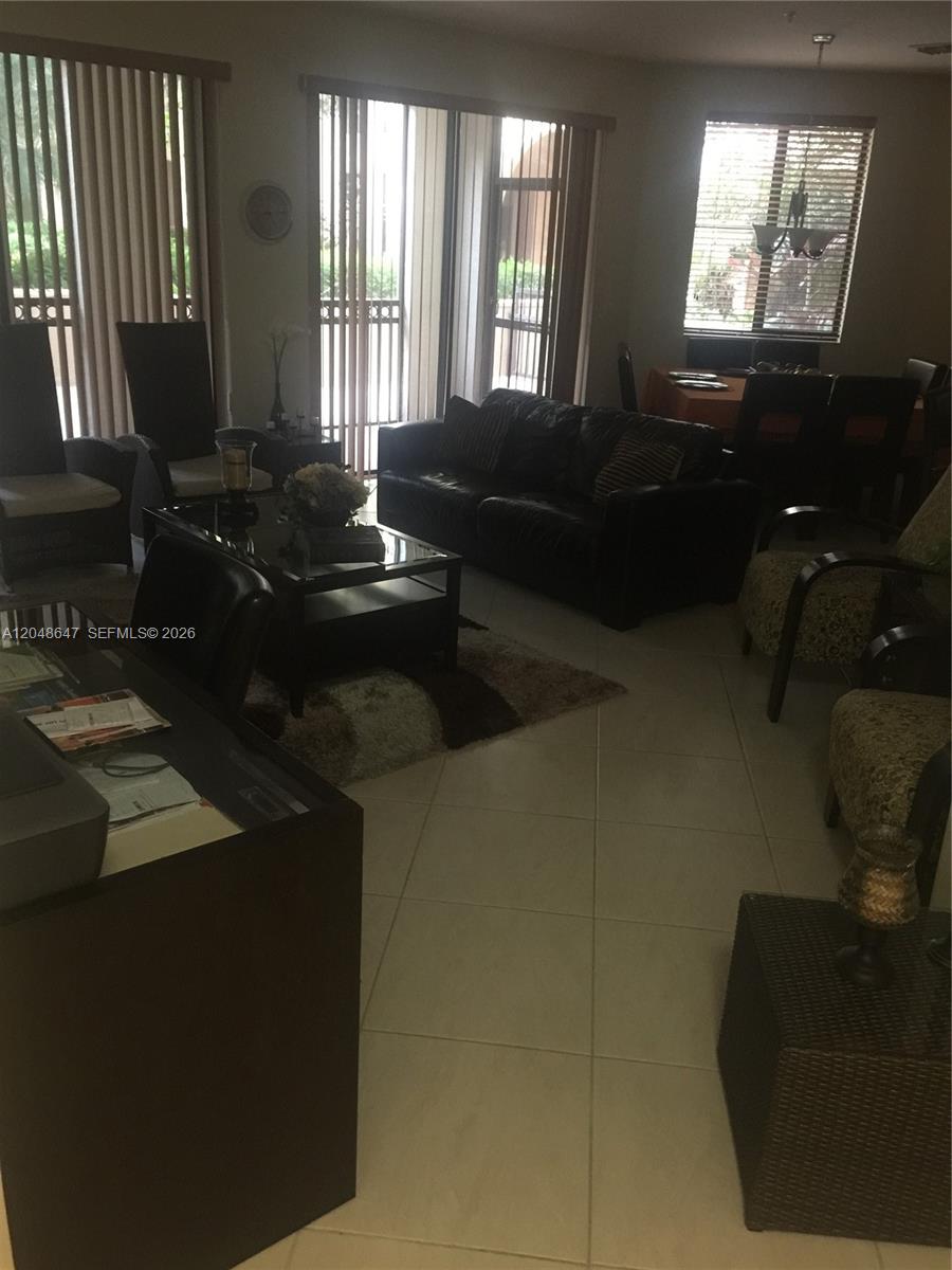 An empty living area features large beige floor tiles, sliding glass doors, and a breakfast bar — 2900 NW 125th Ave # 224, Sunrise FL 33323, SUNRISE, FL