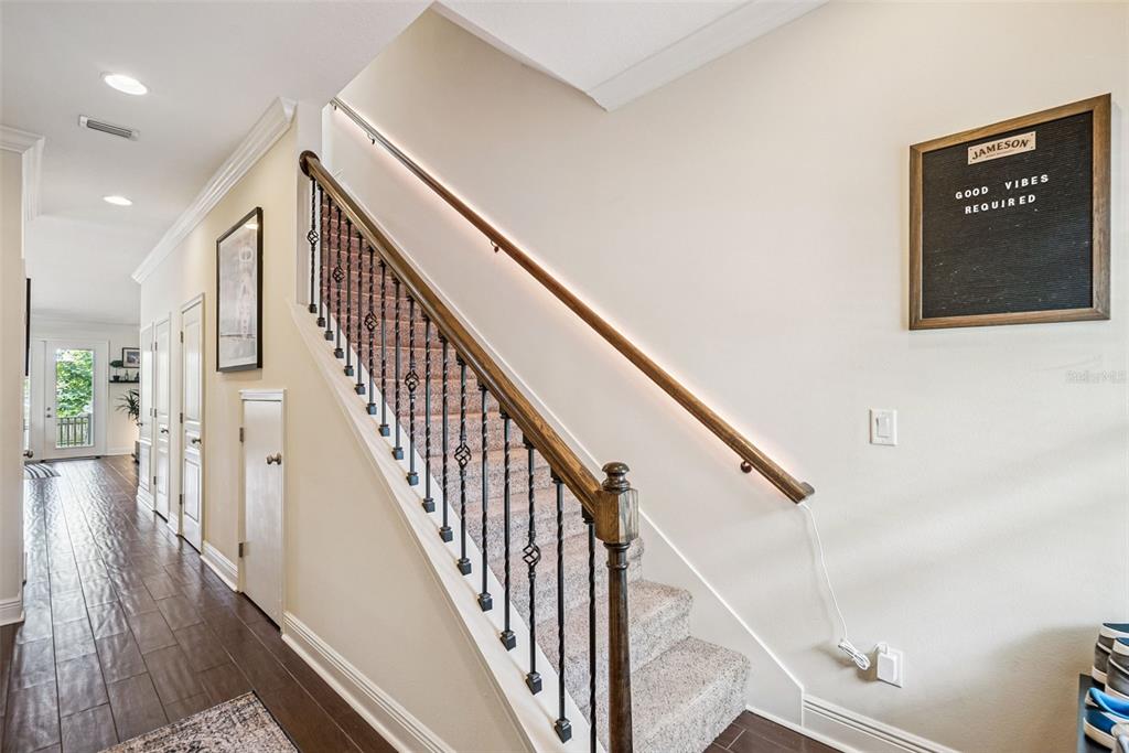 A carpeted staircase with a wooden handrail and iron balusters sits beside a hallway — 2508 E CHURCH STREET, ORLANDO, FL