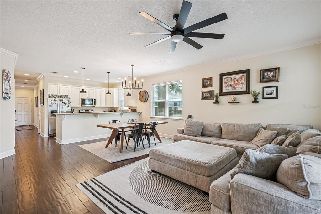 An open-concept living and dining area features a kitchen with white cabinets and wood flooring — 2508 E CHURCH STREET, ORLANDO, FL
