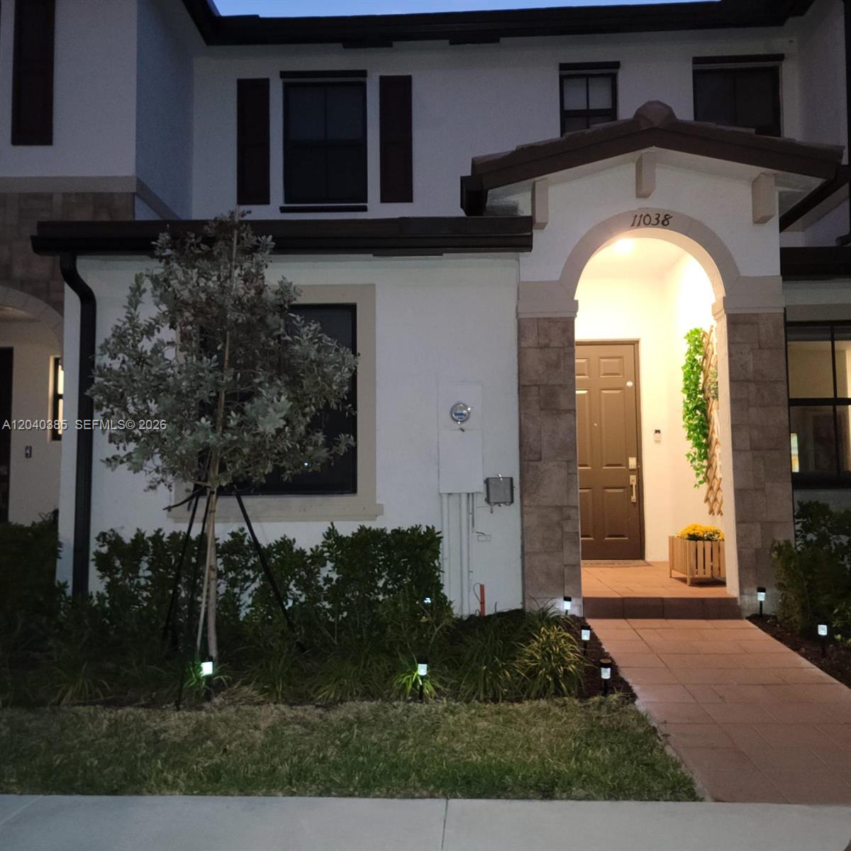 The exterior of a two-story house features a stone-accented entryway, a paved walkway, and landscaping — 11038 W 32nd Ln # 11038, Hialeah FL 33018, HIALEAH, FL