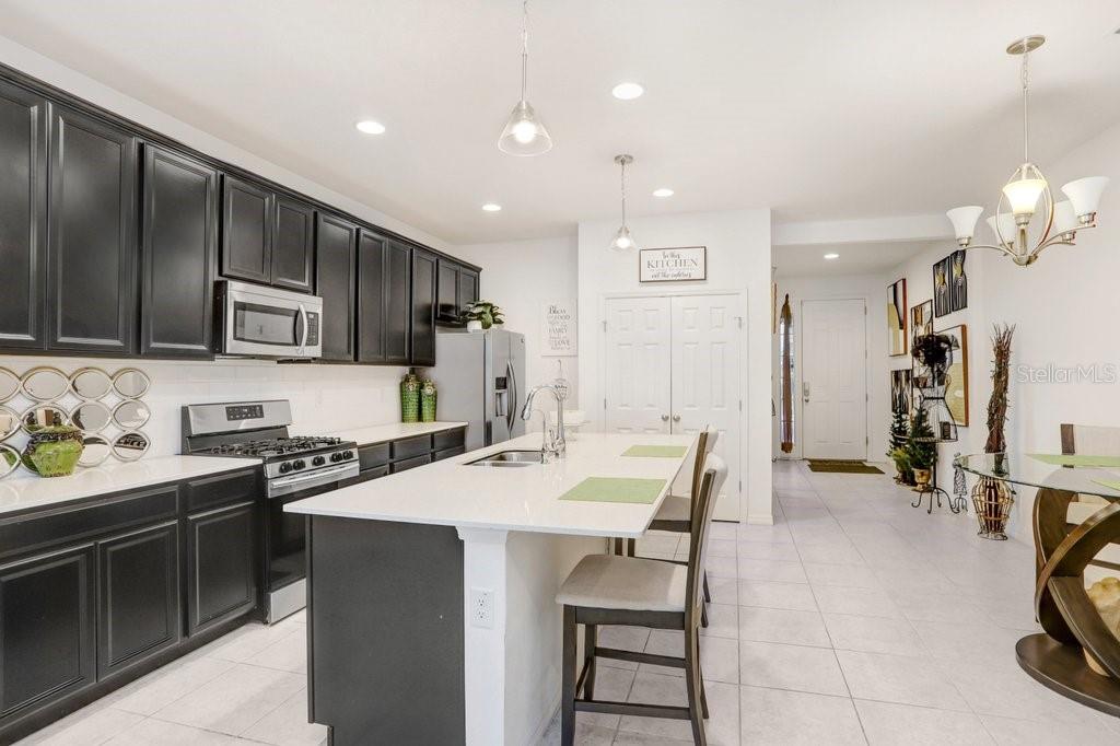 A kitchen features dark cabinetry, white countertops, a central island, and light-colored tile flooring — 6321 CAMINO DRIVE, APOLLO BEACH, FL