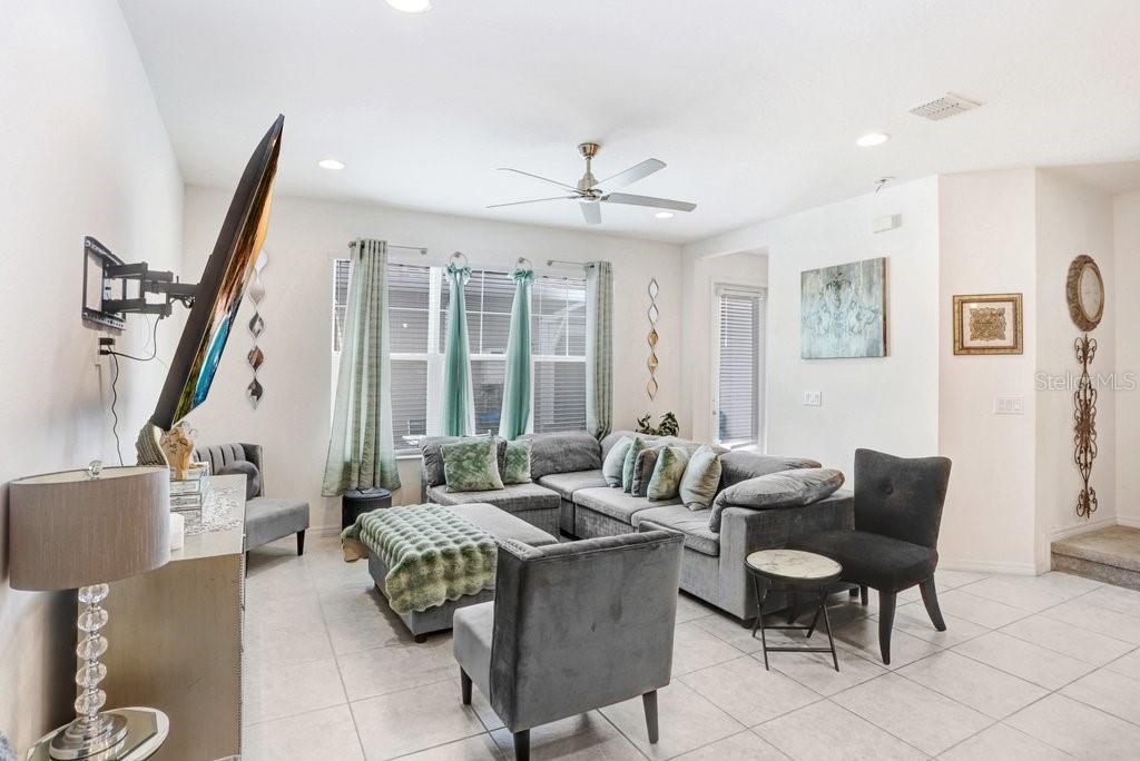 A living room features a grey sectional sofa, a television, and tile flooring — 6321 CAMINO DRIVE, APOLLO BEACH, FL