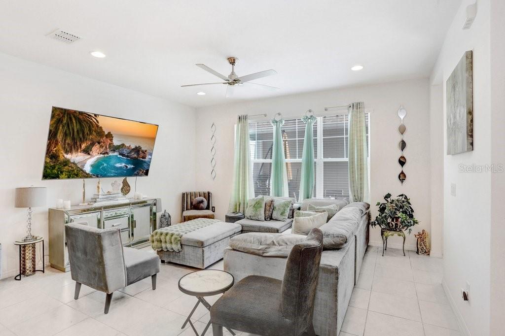 A living room features a large sectional sofa, a mirrored console, and a wall-mounted television — 6321 CAMINO DRIVE, APOLLO BEACH, FL
