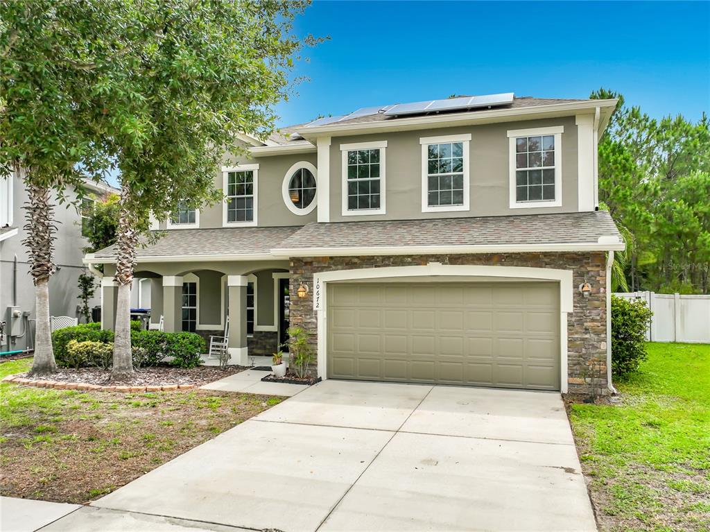 A two-story house with a beige exterior, stone accents, and a two-car garage — 10672 CABBAGE TREE LOOP, ORLANDO, FL