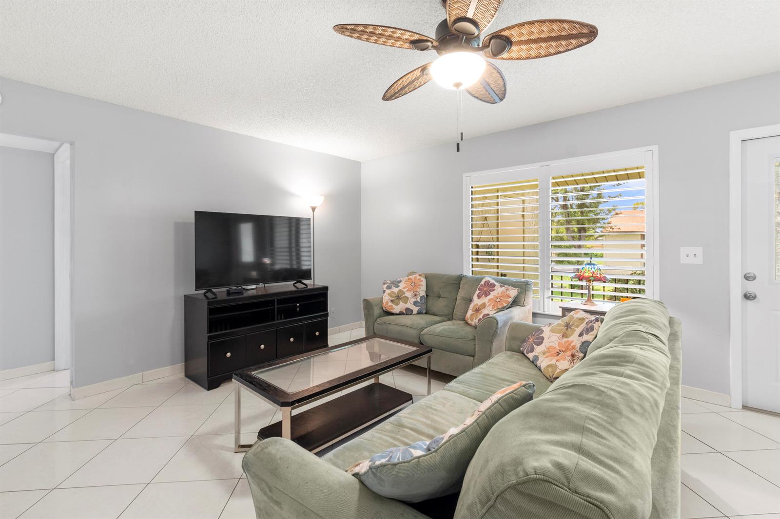 A living room features two green sofas, a glass coffee table, and a ceiling fan — 317 Knotty Pine Circle # 2, FL 33463, FL