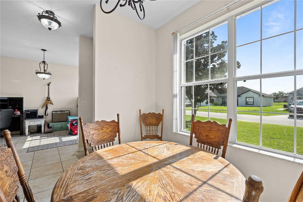 A dining area with a round wooden table, chairs, and a window overlooking a street — 2420 SE 75TH BOULEVARD, BUSHNELL, FL