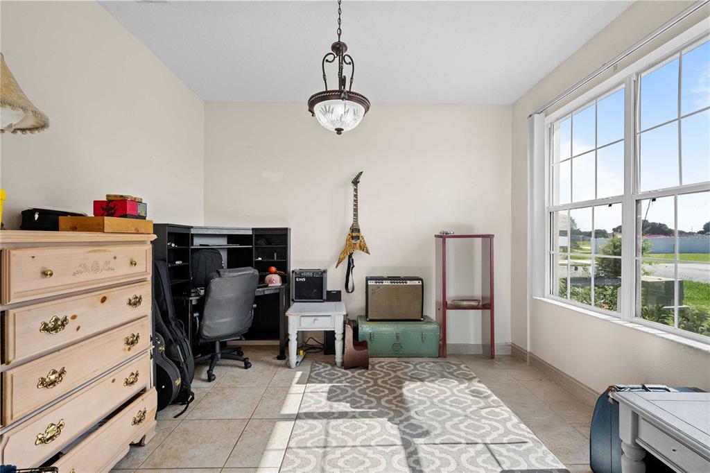 A room with tile flooring, a desk, musical equipment, and a large window — 2420 SE 75TH BOULEVARD, BUSHNELL, FL