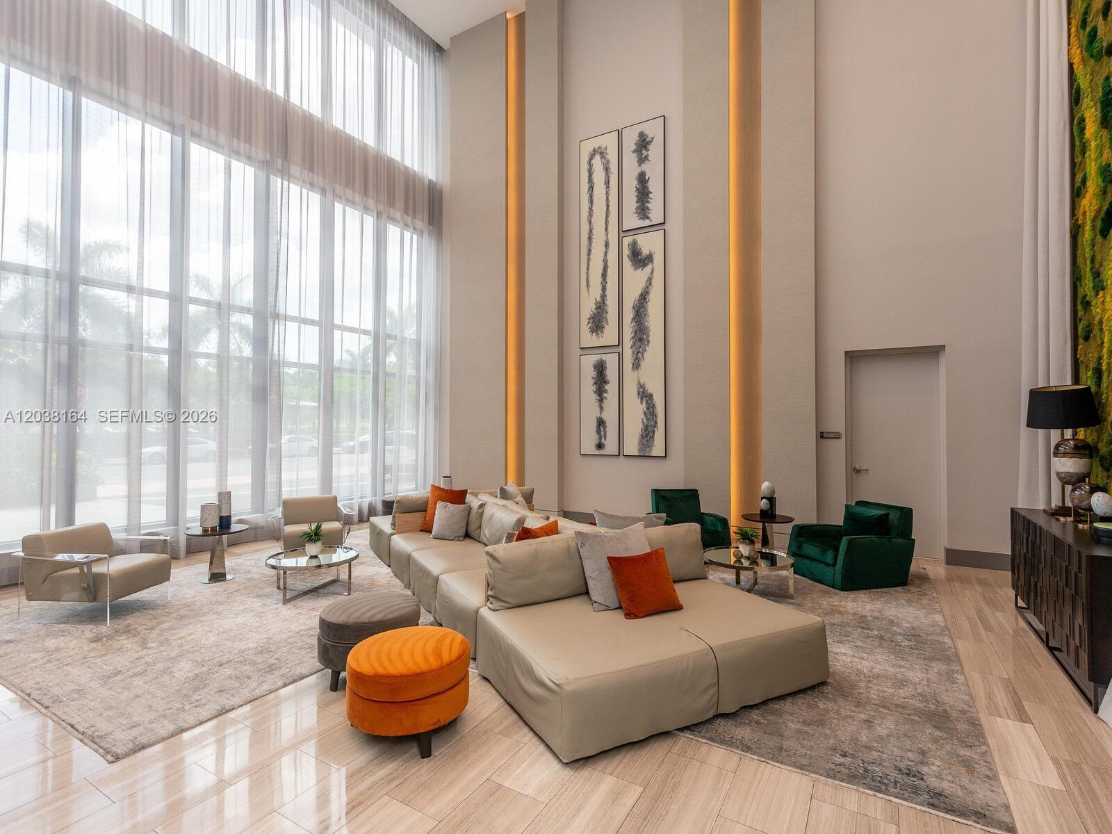 A modern, high-ceilinged lounge features a large sectional sofa, floor-to-ceiling windows, and accent lighting — 5350 NW 84th Ave # 1018, Doral FL 33166, DORAL, FL