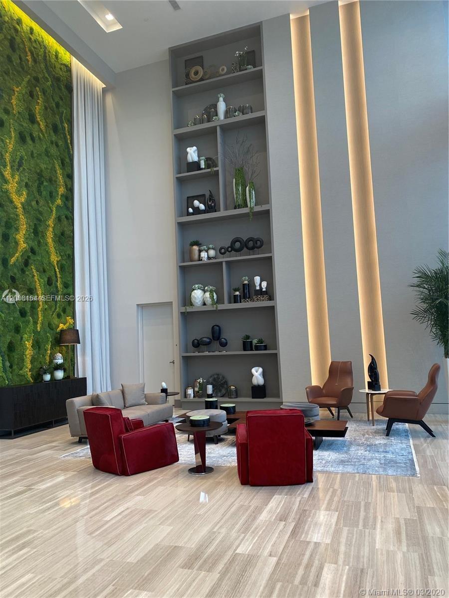 A spacious lobby features a tall built-in bookshelf, a moss wall, and modern seating — 5350 NW 84th Ave # 1018, Doral FL 33166, DORAL, FL