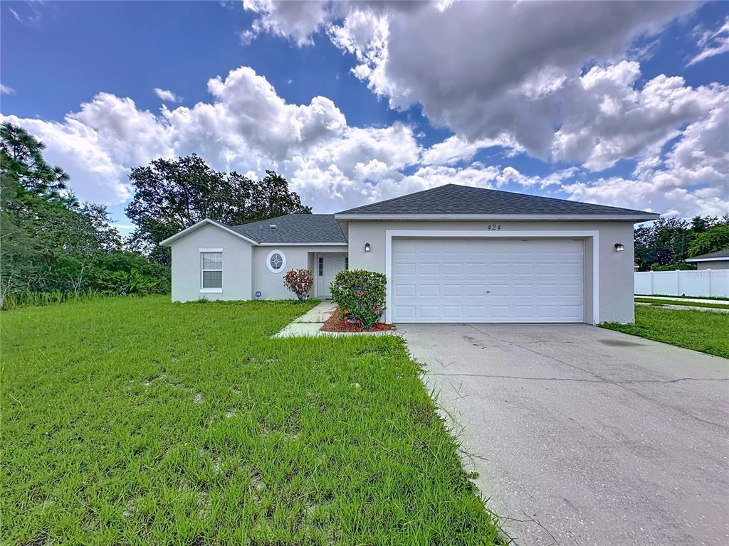 A single-story house with a white garage door, light-colored stucco exterior, and a concrete driveway — 424 DANUBE WAY, KISSIMMEE, FL