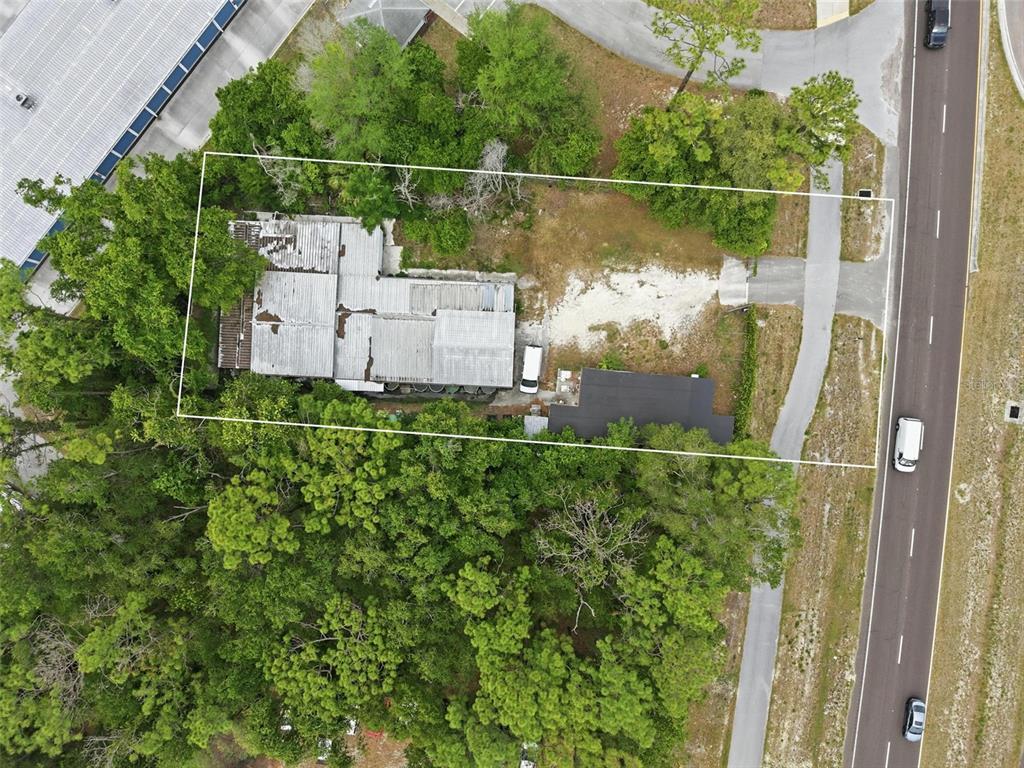 An aerial view shows a rectangular lot containing two buildings, trees, and a gravel driveway — 15520 CORTEZ BOULEVARD, BROOKSVILLE, FL