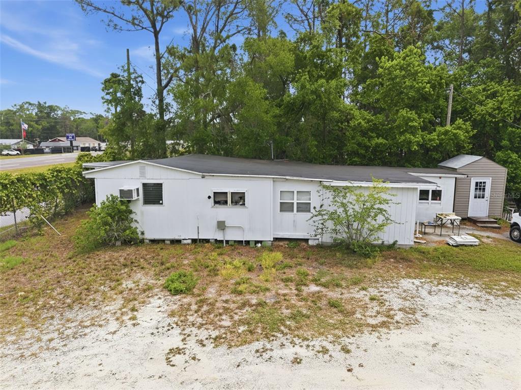 A white single-story mobile home with a flat roof sits on a sandy, grassy lot — 15520 CORTEZ BOULEVARD, BROOKSVILLE, FL