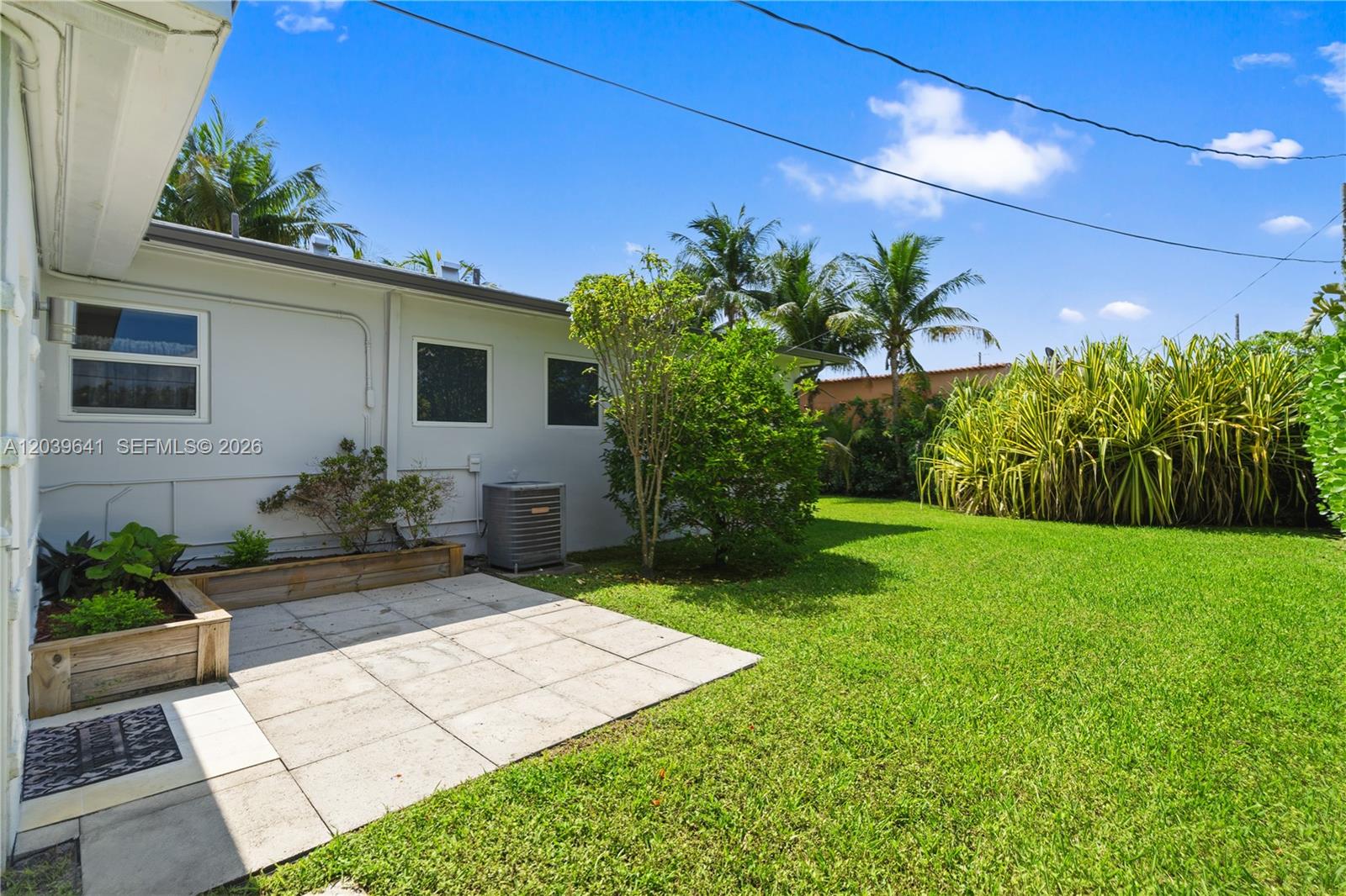 A backyard features a small paved patio, a wooden planter box, and a grassy lawn — 5790 SW 3rd St, Miami FL 33144, MIAMI, FL