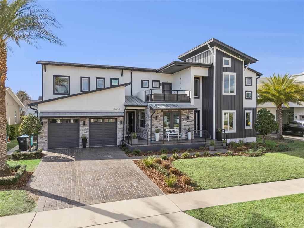 A two-story modern house features a brick driveway, stone accents, and a second-floor balcony — 12618 SNELL LANE, ORLANDO, FL
