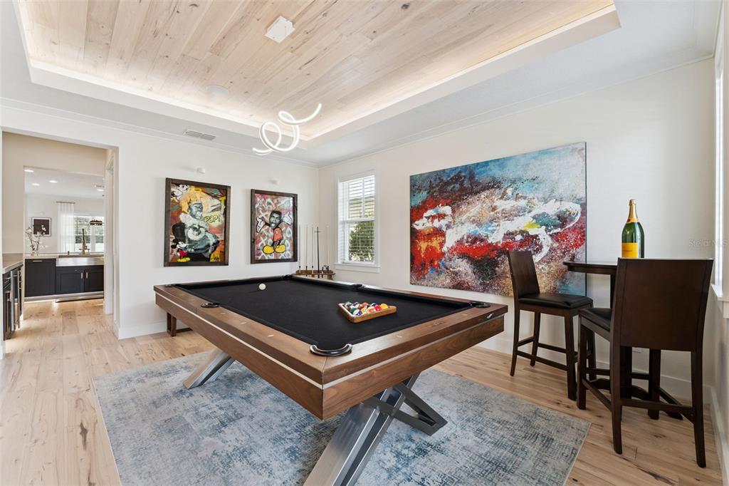 A game room features a pool table, modern light fixture, wood ceiling, and colorful wall art — 12618 SNELL LANE, ORLANDO, FL