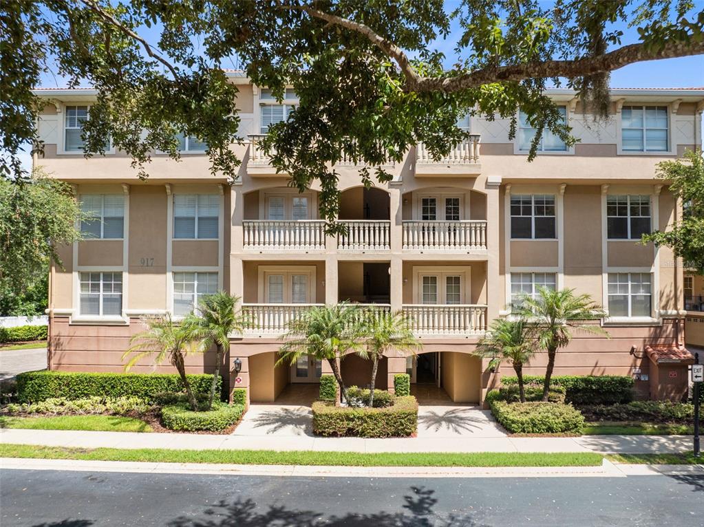 A three-story apartment building with balconies, tan stucco walls, and palm trees in front — 917 LOTUS VISTA DRIVE UNIT 201, ALTAMONTE SPRINGS, FL