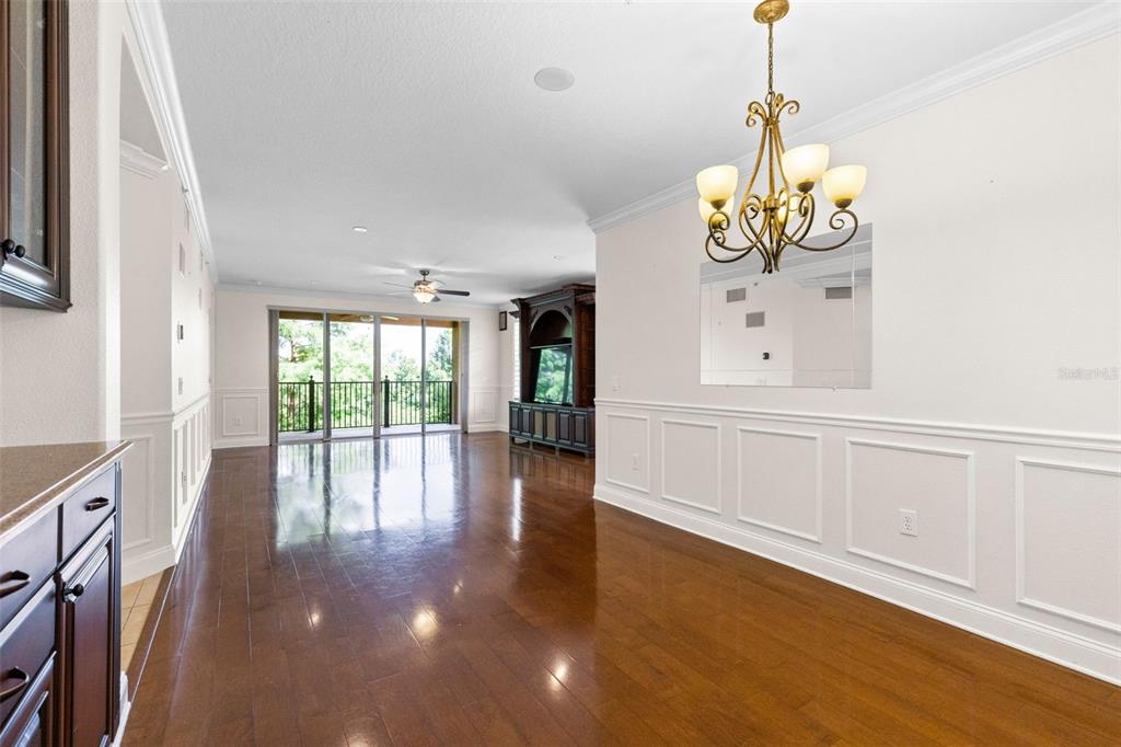 A dining room with hardwood floors, white wainscoting, a chandelier, and a view of a balcony — 917 LOTUS VISTA DRIVE UNIT 201, ALTAMONTE SPRINGS, FL
