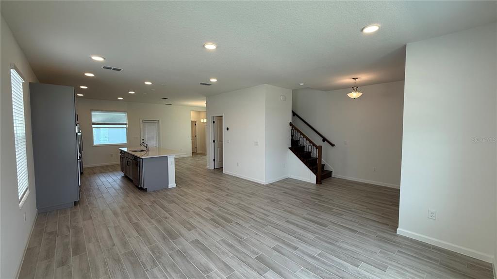 An open-concept kitchen and living area features gray cabinetry, a central island, and wood-look flooring — 17125 BEACHGRASS ALLEY, WINTER GARDEN, FL