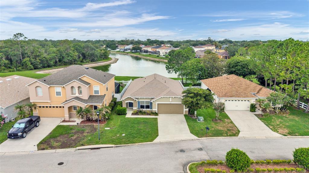 An aerial view shows three suburban houses with driveways and lawns bordering a small lake — 3005 PARK RIDGE AVENUE, MULBERRY, FL