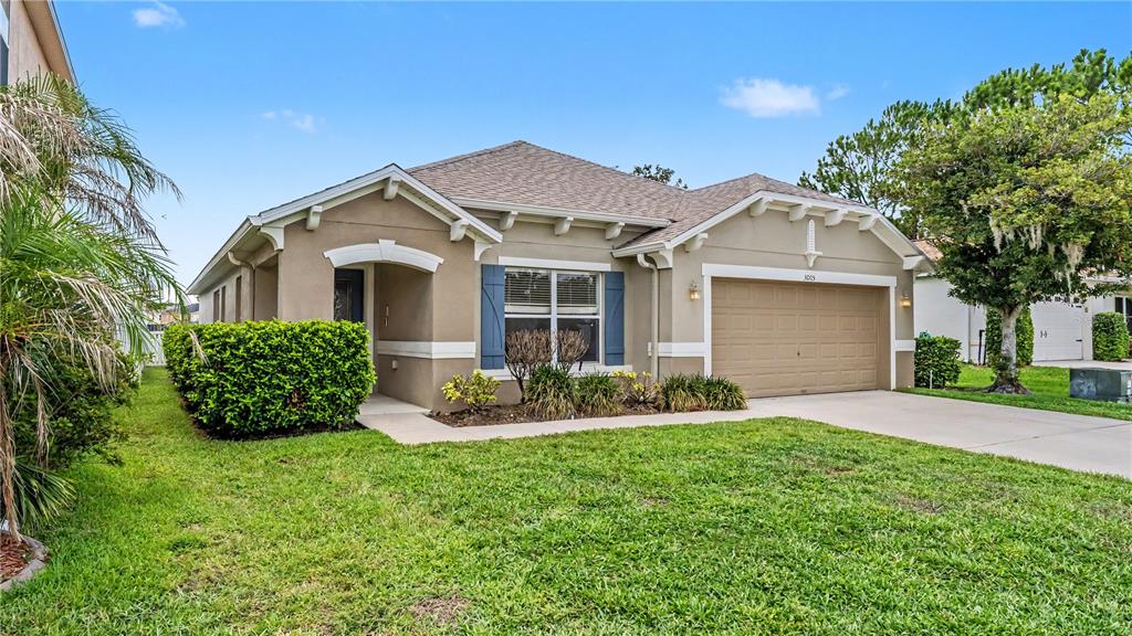 A single-story house with a tan stucco exterior, blue shutters, and a two-car garage — 3005 PARK RIDGE AVENUE, MULBERRY, FL