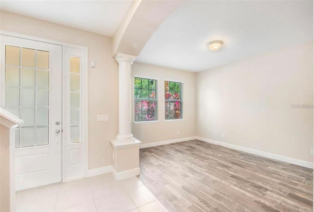An entryway with a white front door, a decorative column, and light wood-look flooring — 8642 VIA TAVOLERIA WAY, WINDERMERE, FL