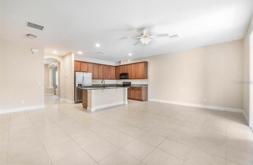 An open-concept kitchen with wood cabinets, stainless steel appliances, and a central island — 8642 VIA TAVOLERIA WAY, WINDERMERE, FL