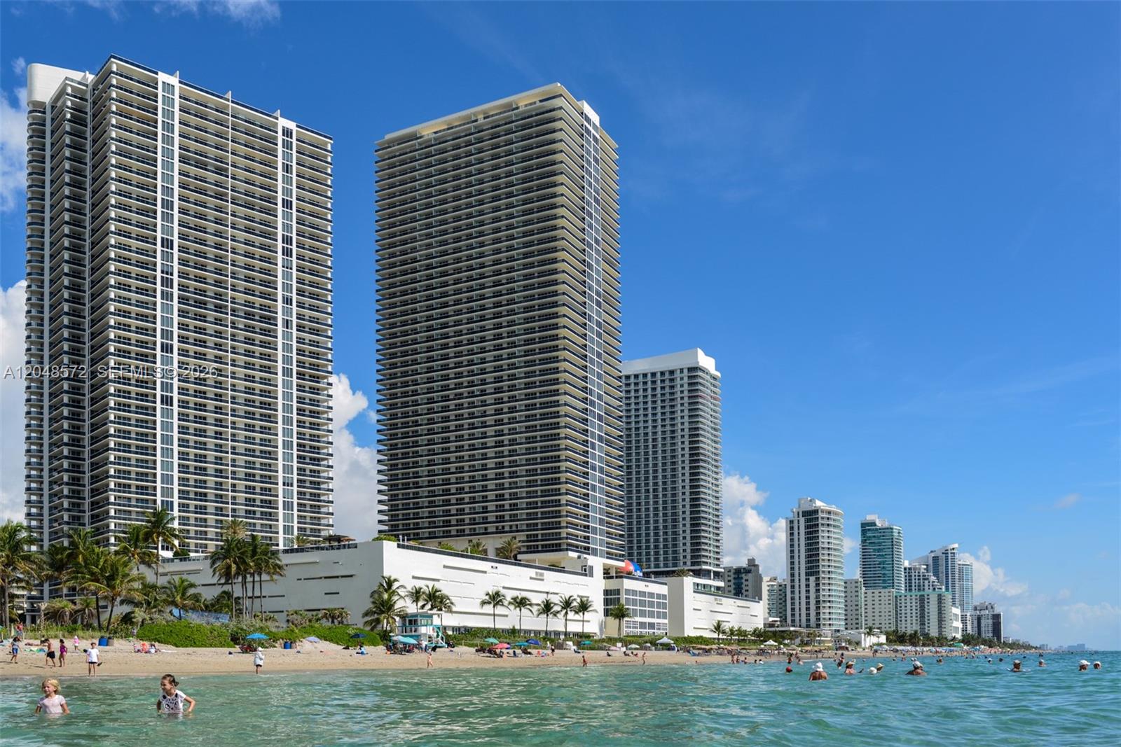 Tall residential towers stand along a sandy beach with people swimming in the ocean — 1800 S Ocean Dr # 2203, Hallandale Beach FL 33009, HALLANDALE BEACH, FL