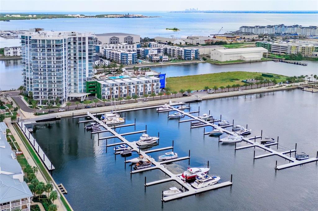 An aerial view shows a modern apartment complex situated next to a boat-filled marina — 5120 MARINA WAY UNIT 9907, TAMPA, FL
