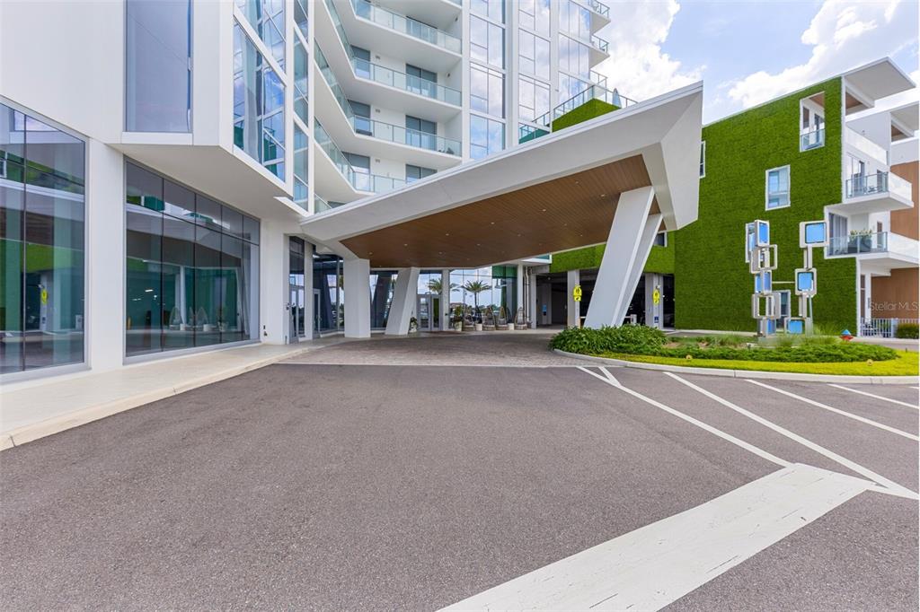The exterior of a modern building features a large porte-cochère and a green wall — 5120 MARINA WAY UNIT 9907, TAMPA, FL