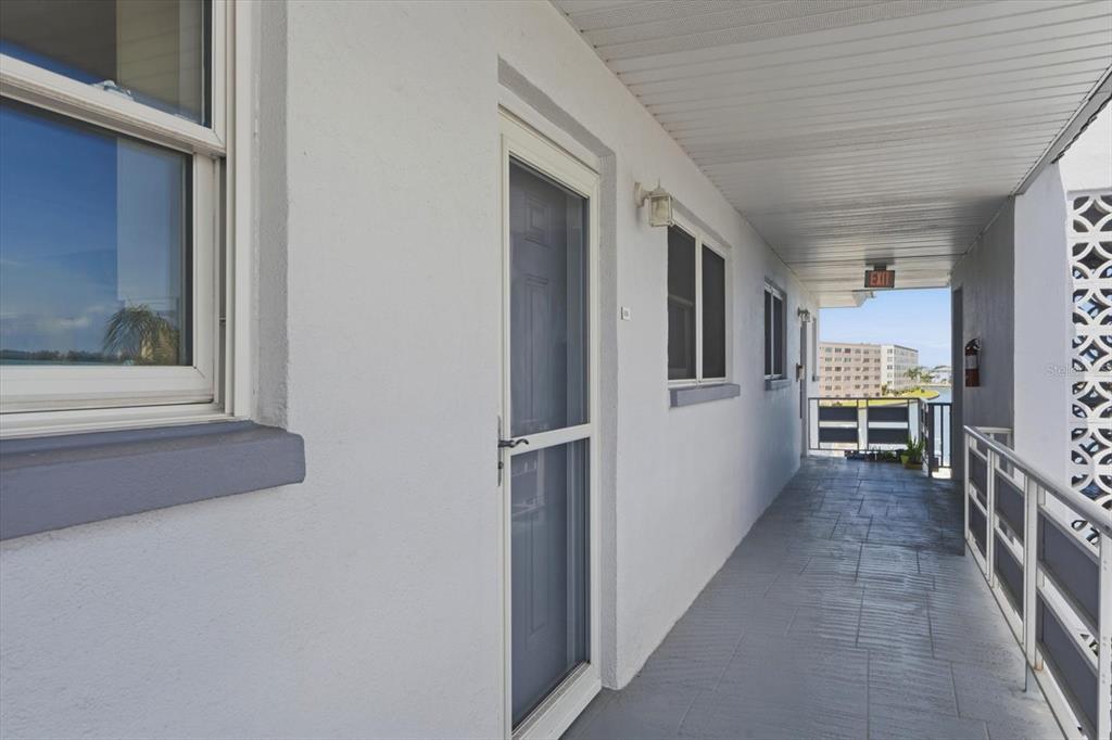 An exterior walkway with a screen door, windows, and a metal railing overlooking the water — 3018 59TH STREET S UNIT 414, GULFPORT, FL